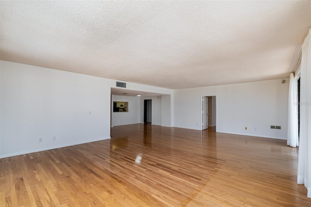 unfurnished room with a textured ceiling and light hardwood / wood-style flooring