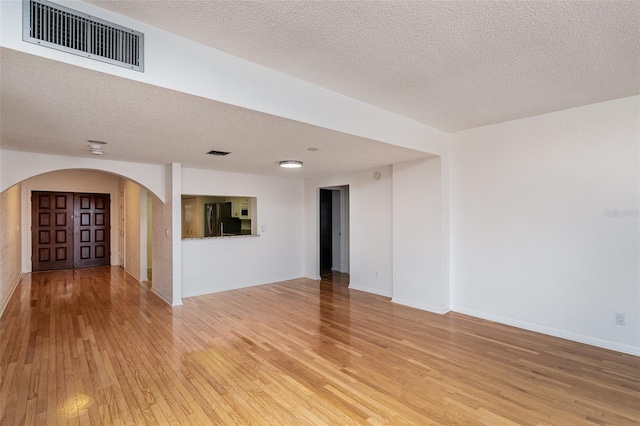 unfurnished room featuring a textured ceiling and light wood-type flooring