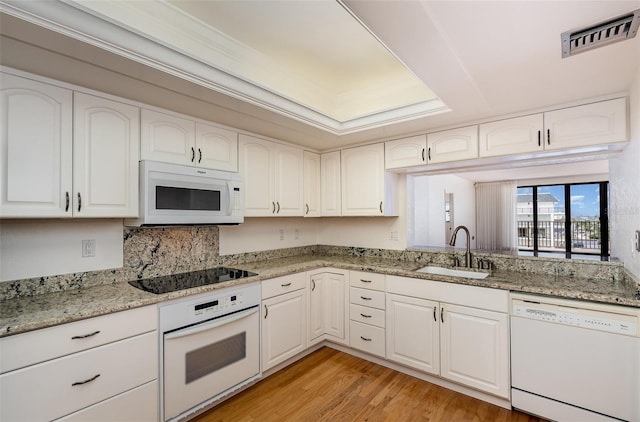 kitchen with white appliances, sink, white cabinetry, light stone counters, and light hardwood / wood-style flooring