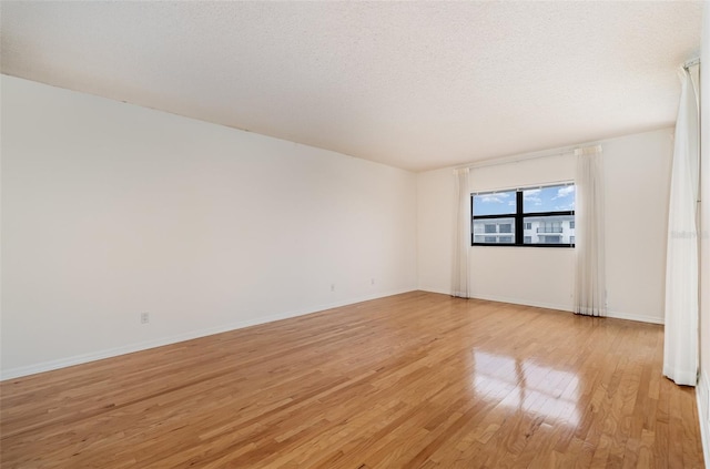 spare room featuring light hardwood / wood-style flooring and a textured ceiling