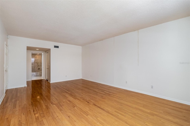 spare room with a textured ceiling and light hardwood / wood-style flooring