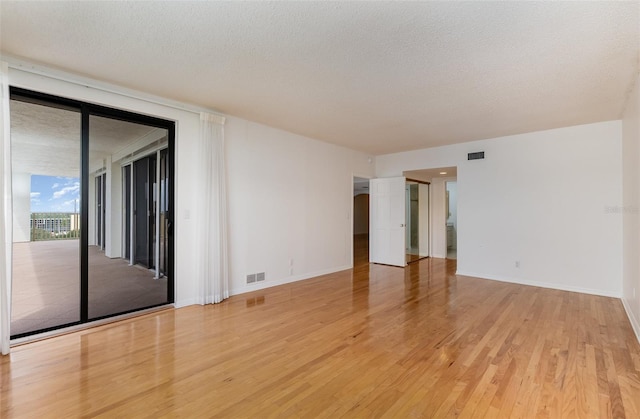 unfurnished room with light hardwood / wood-style floors and a textured ceiling