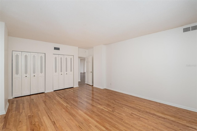 unfurnished bedroom featuring light hardwood / wood-style floors and multiple closets