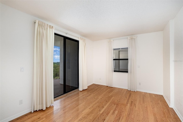 spare room with a textured ceiling and light wood-type flooring