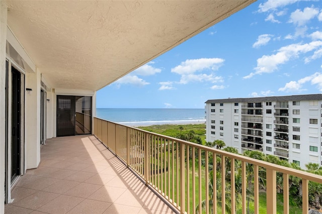 balcony with a water view and a view of the beach