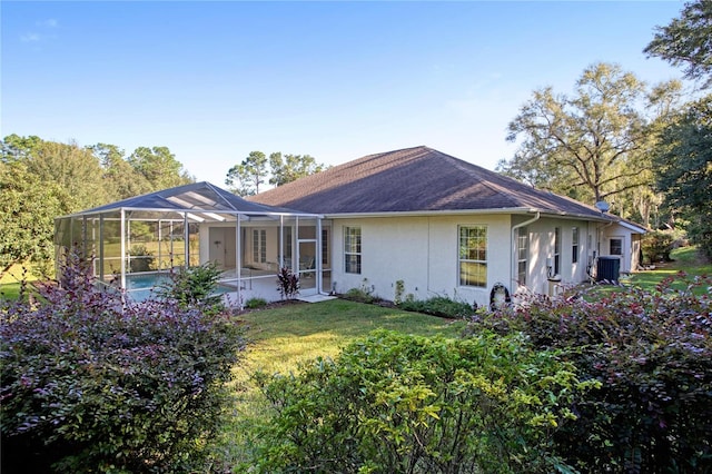 view of front of home with a front yard, central AC unit, and a lanai