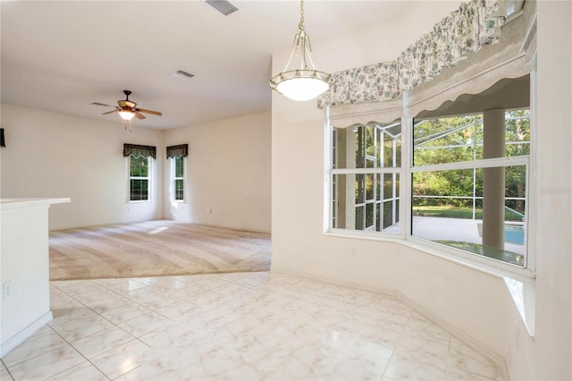 unfurnished room with ceiling fan, light colored carpet, and a wealth of natural light