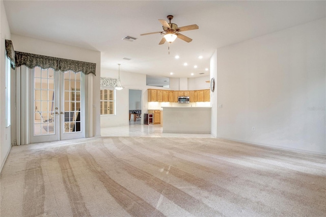 unfurnished living room with light carpet, french doors, and ceiling fan