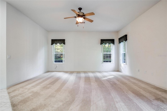 unfurnished room featuring ceiling fan, a healthy amount of sunlight, and light colored carpet