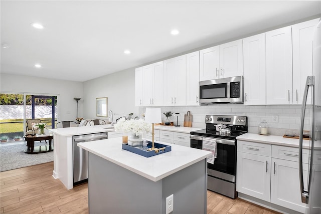 kitchen featuring kitchen peninsula, stainless steel appliances, a center island, and light wood-type flooring