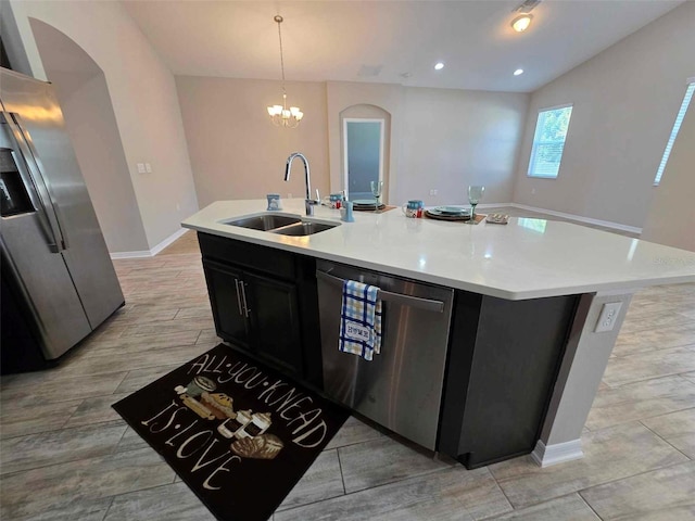 kitchen with an inviting chandelier, sink, hanging light fixtures, an island with sink, and stainless steel appliances