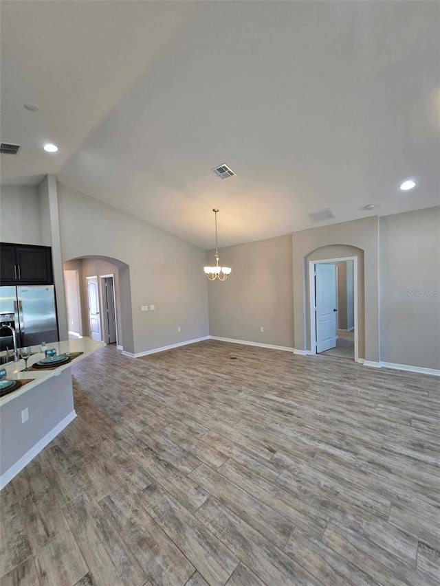 interior space featuring lofted ceiling, light wood-type flooring, and a notable chandelier