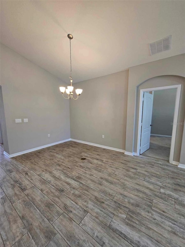 spare room with light hardwood / wood-style floors and an inviting chandelier