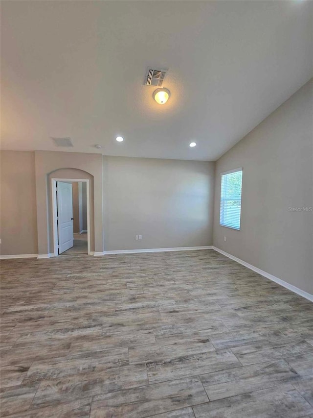 spare room featuring light hardwood / wood-style flooring and vaulted ceiling