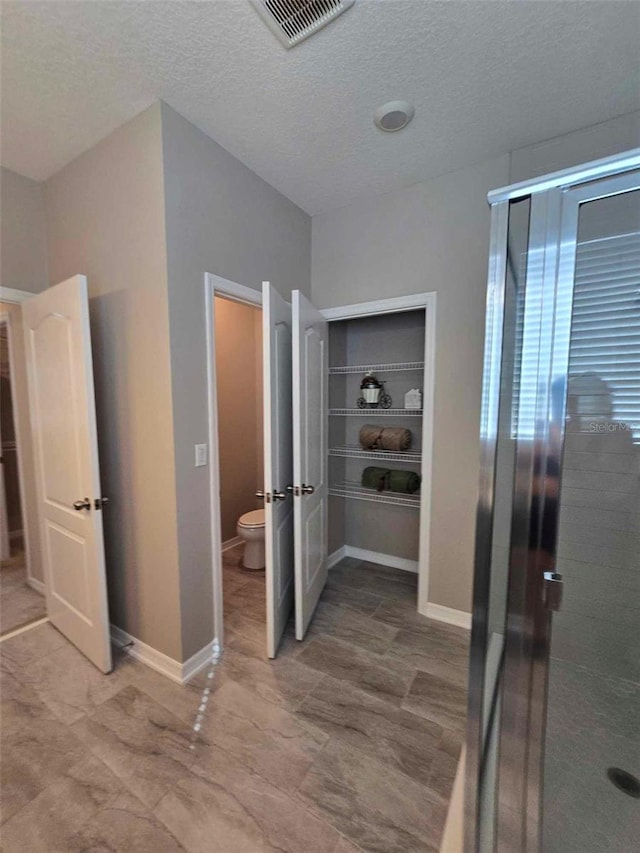 bathroom with a shower, toilet, and a textured ceiling