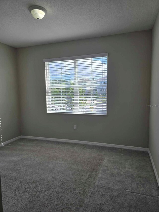 empty room with a textured ceiling and dark carpet