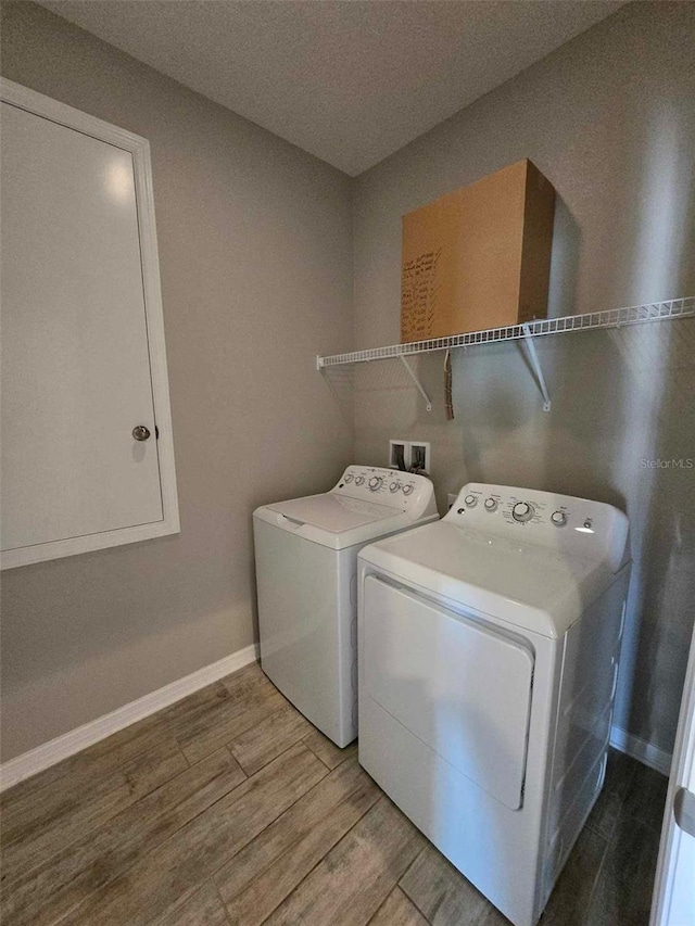 washroom featuring washing machine and dryer, light hardwood / wood-style flooring, and a textured ceiling