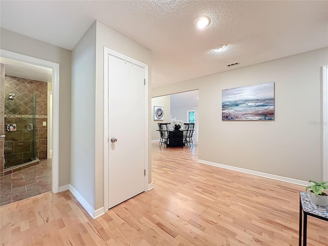 hallway featuring light hardwood / wood-style floors and a textured ceiling