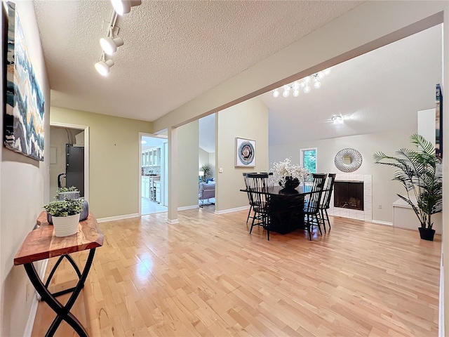 dining room with a textured ceiling, light wood-type flooring, and a fireplace