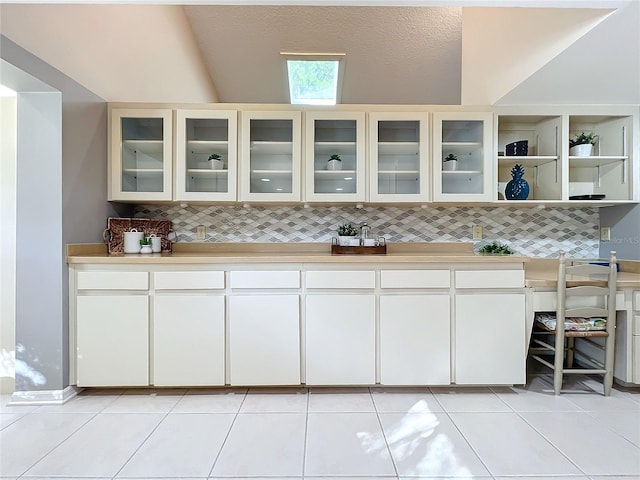 kitchen featuring decorative backsplash, white cabinets, a textured ceiling, and light tile patterned floors