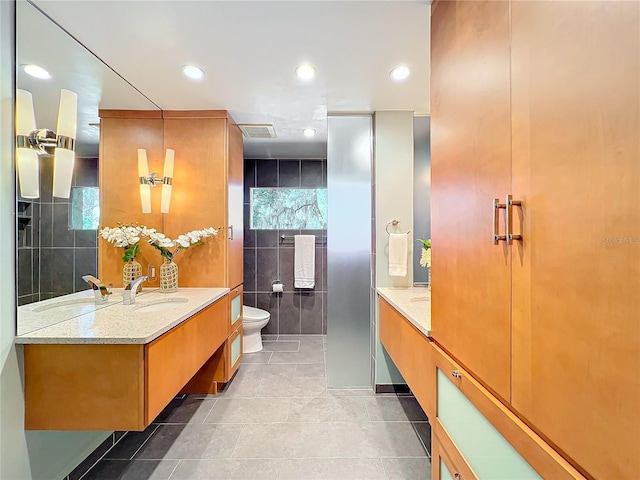 bathroom featuring vanity, toilet, tile patterned floors, and tile walls