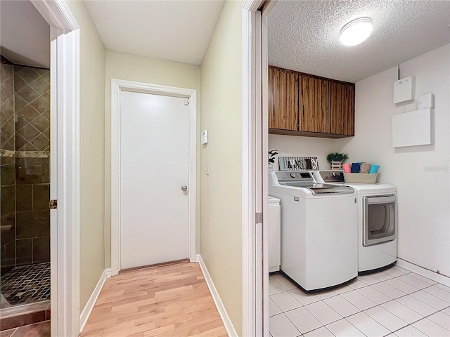 washroom featuring light hardwood / wood-style flooring, independent washer and dryer, a textured ceiling, and cabinets