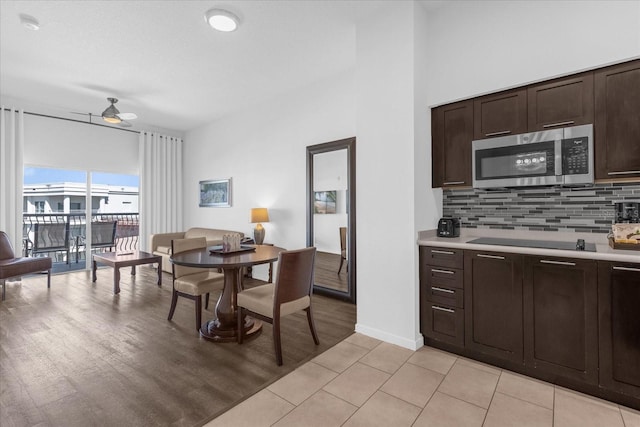 kitchen featuring decorative backsplash, black electric cooktop, dark brown cabinetry, light hardwood / wood-style floors, and ceiling fan