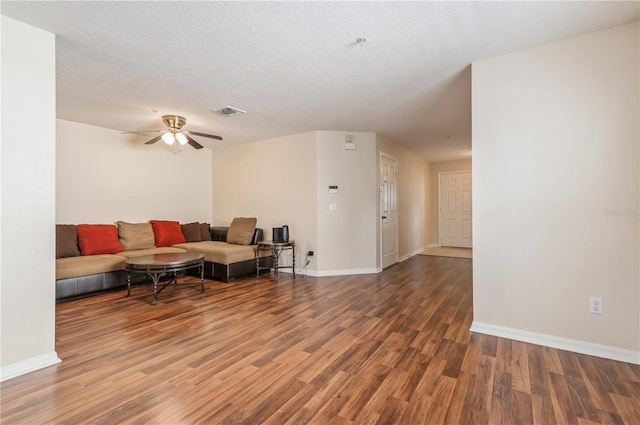 living room with a textured ceiling, dark wood-type flooring, and ceiling fan