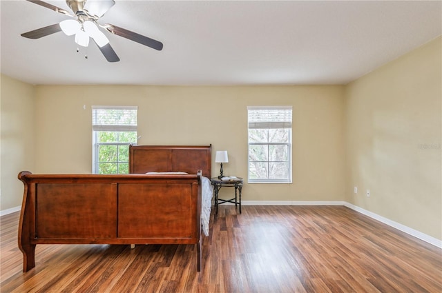 bedroom featuring ceiling fan, multiple windows, and dark hardwood / wood-style flooring