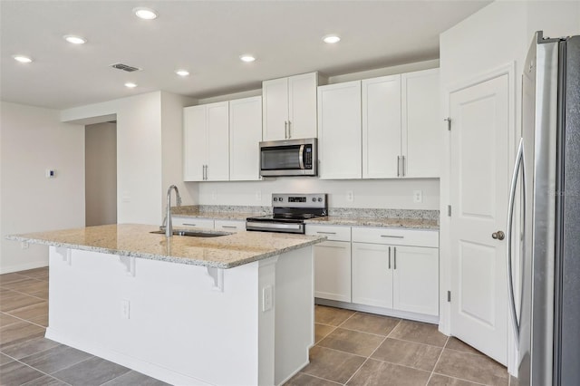 kitchen with white cabinets, stainless steel appliances, a center island with sink, and sink