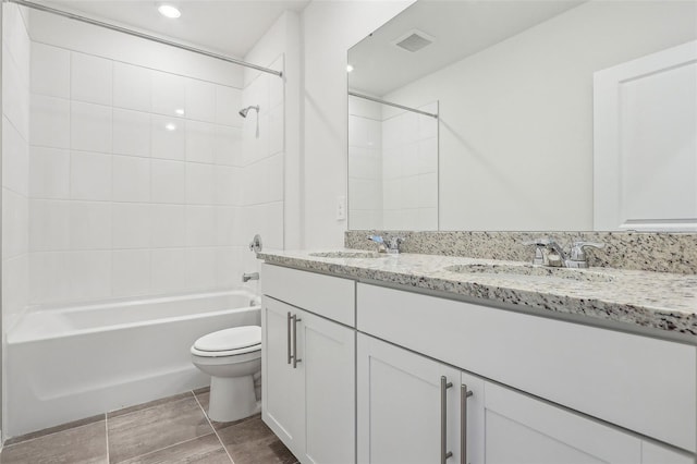 full bathroom with tiled shower / bath, vanity, and toilet