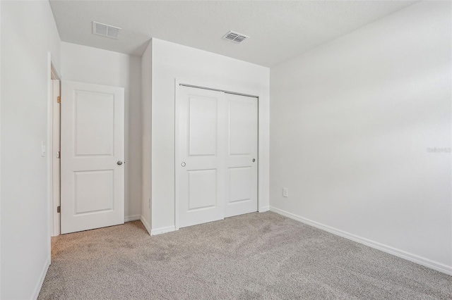 unfurnished bedroom with light carpet and a closet