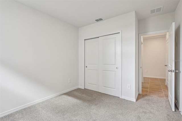 unfurnished bedroom featuring light colored carpet and a closet