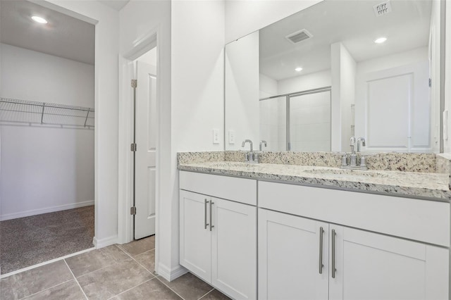 bathroom with tile patterned flooring, vanity, and a shower with door