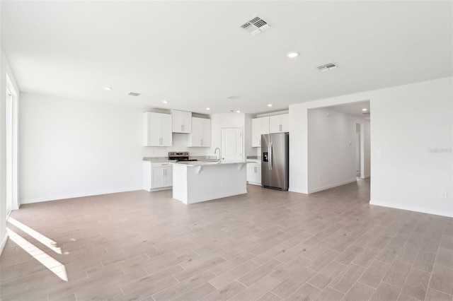 kitchen with white cabinetry, sink, stainless steel appliances, an island with sink, and light wood-type flooring