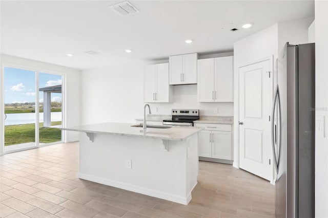 kitchen with a kitchen bar, appliances with stainless steel finishes, a kitchen island with sink, sink, and white cabinets