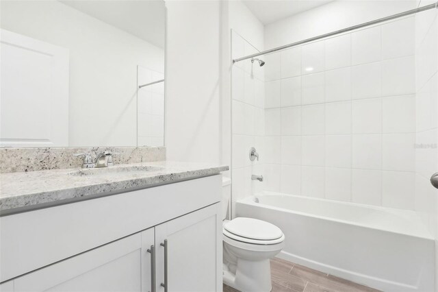 full bathroom featuring toilet, vanity, and tiled shower / bath