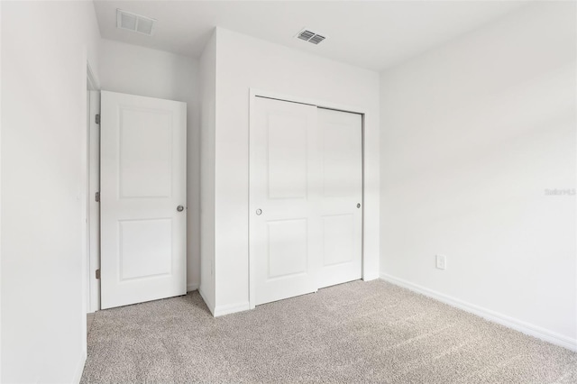 unfurnished bedroom featuring light carpet and a closet