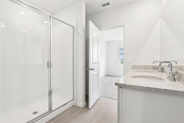 bathroom with a shower with door and vanity