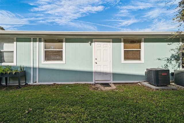 entrance to property with a lawn and cooling unit