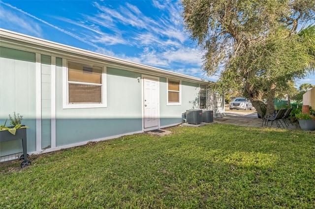 rear view of property featuring central AC and a lawn