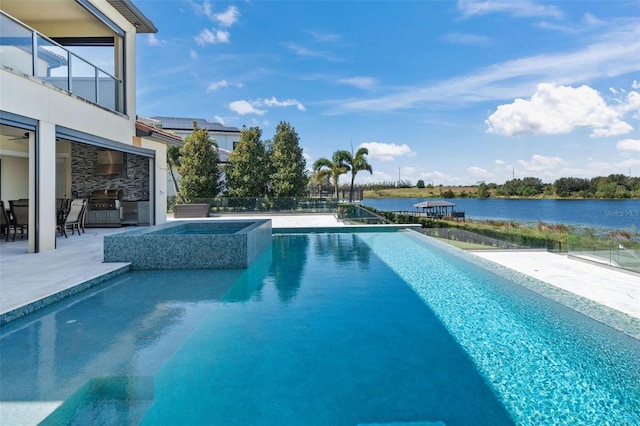 view of pool with a patio, an in ground hot tub, and a water view