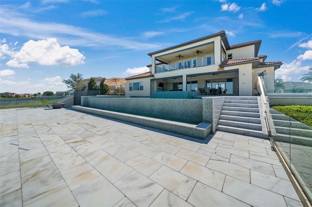 back of property featuring a patio, ceiling fan, a water view, and a balcony