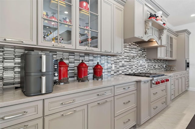 kitchen with light tile patterned flooring, backsplash, custom exhaust hood, stainless steel gas stovetop, and crown molding