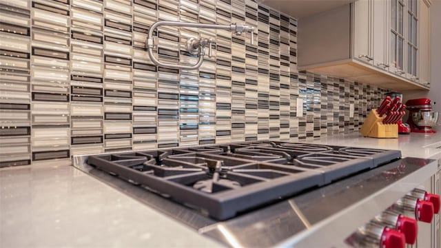 details with stainless steel gas stovetop and tasteful backsplash