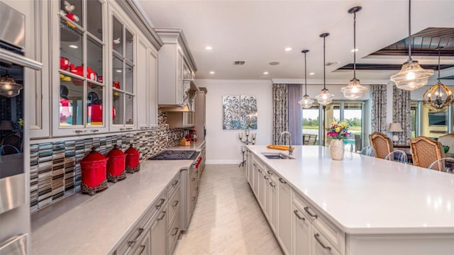 kitchen with hanging light fixtures, a spacious island, stainless steel gas stovetop, ornamental molding, and sink