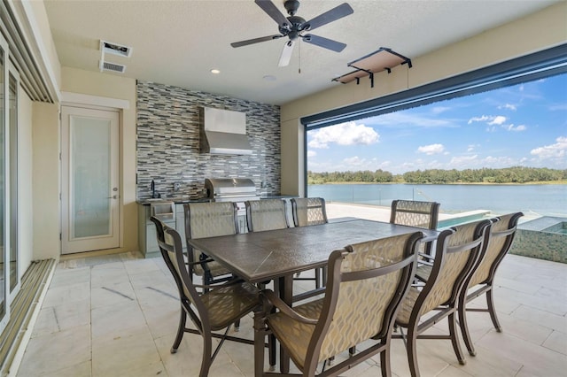 dining area featuring a textured ceiling, sink, a water view, and ceiling fan