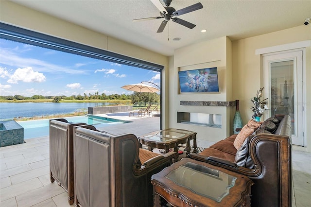 view of patio / terrace featuring a pool with hot tub, a water view, and ceiling fan