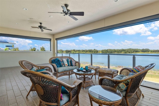 sunroom with plenty of natural light, a water view, and ceiling fan