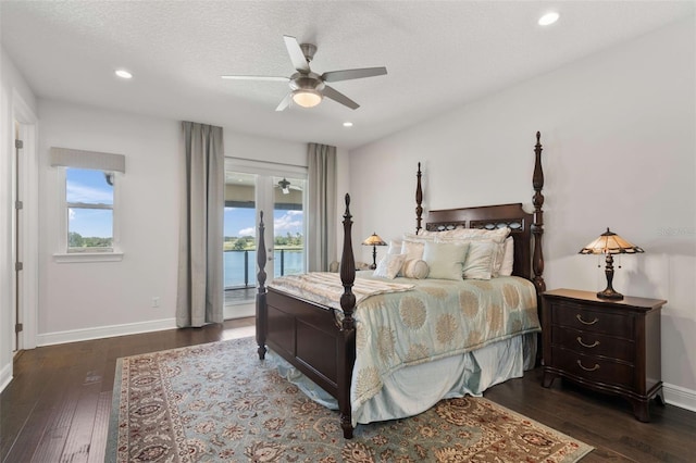 bedroom featuring access to exterior, ceiling fan, a textured ceiling, a water view, and dark hardwood / wood-style flooring